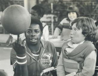 Round it goes. Reggie Franklin of the Harlem Globetrotters makes 9-year-old Jennifer Skalenda's eyes pop with his basketball-twirling during his visit(...)