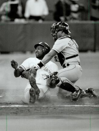A step ahead: Joe Carter slides into home under tha tag of Ranger catcher Ivan Rodriguez for a Jay run last night at the SkyDome