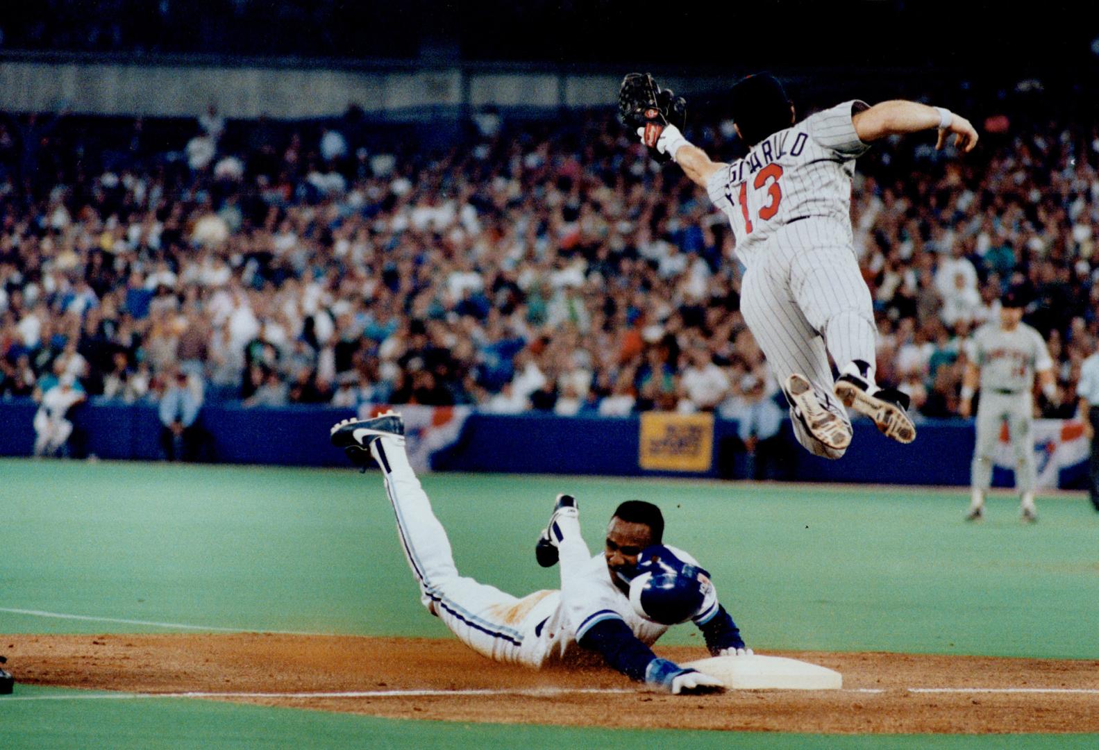 Hats off: Speedy Blue Jay baserunner Devon White loses his batting helmet as he slides into third base under a leaping Mike Pagliarulo