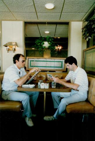 Pitchers Tom Henke, left, and John Cerutti study the breakfast menus in a restaurant near the team hotel