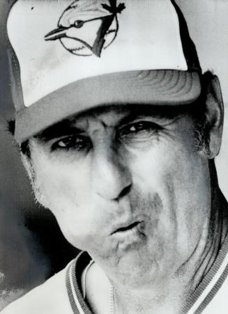 A Veteran at work: First base coach Harry Warner, above, unlike youthful Blue Jay players, has refined art of chewing tobacco over many seasons