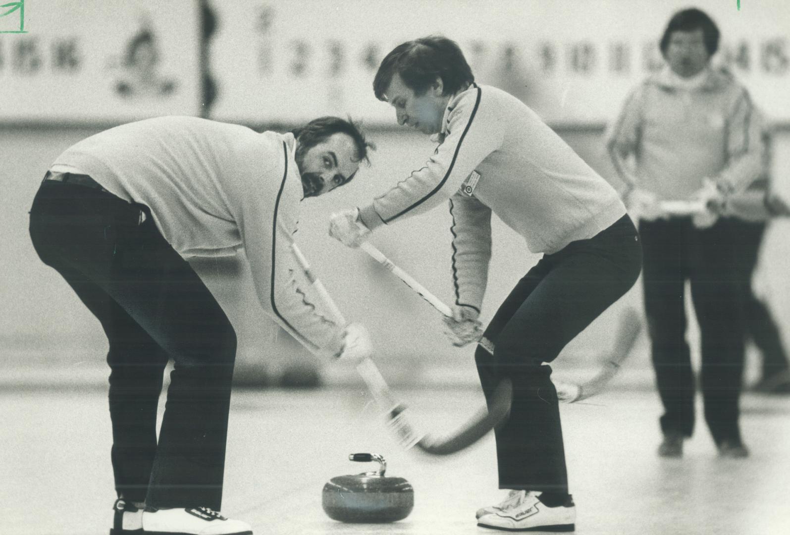 Sweeping out the house. Les Sicoli (left), skip of the Ontario deaf provincial curling championship foursome, uses body English to help his sweepers G(...)