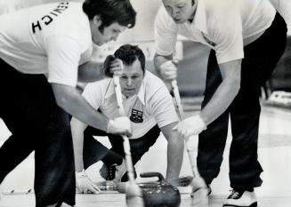 Ontario curlers Ed Werenich, left, and Ron Green, right, bend their brooms as skip Paul Savage closely follows path of rock during opening round match(...)