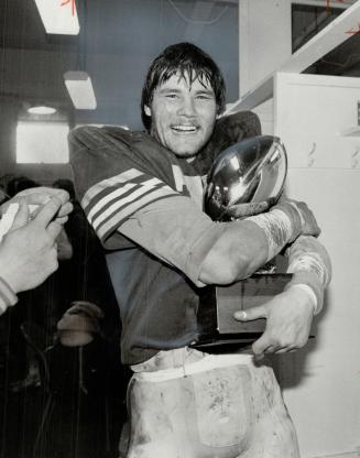 Guess who won? That's Alberta's Gord Syme clutching the trophy he won yesterday as the outstanding defensive player in Golden Bears' 40-21 defeat of Ottawa Gee Gees