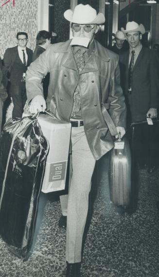 Loaded down with luggage, centre Basil Bark of Stampeders arrives at Park Plaza