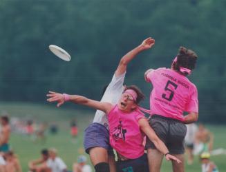 Playing the ultimate way. Dave Northrup, right, of Rochester's Fuschia Shock squad, jumps into a Frisbee tray with a teammate, centre, and an opponent(...)