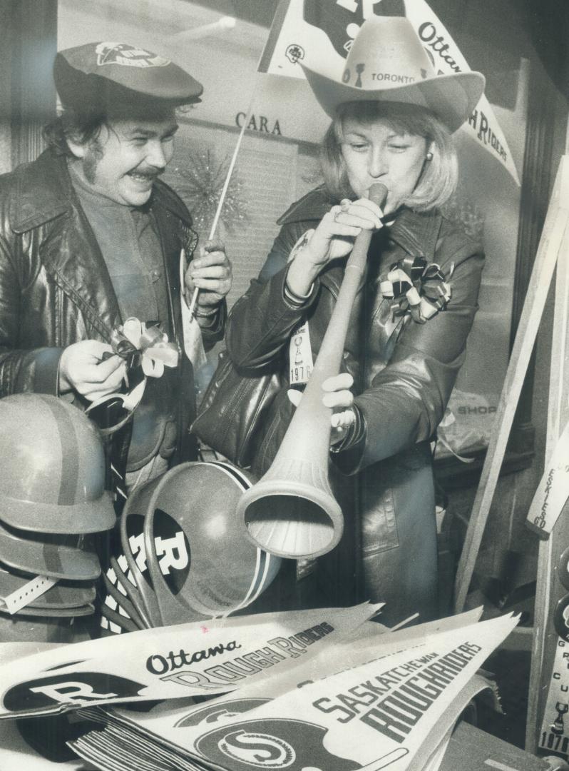 Blowing her horn for her Grey Cup favorites, Cathy Hagey of Ottawa looks over the football regalia Jerry Antoniuk is selling fans on Front St. near Union Station