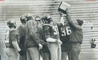 Alouette special teams coach Larry Pasquale (toque) holds up a playbook for his squad yesterday at Exhibition Stadium
