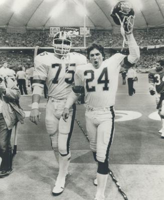 Argos' Ken McEachern (24) and Steve Del Col (75) walk off field triumphantly