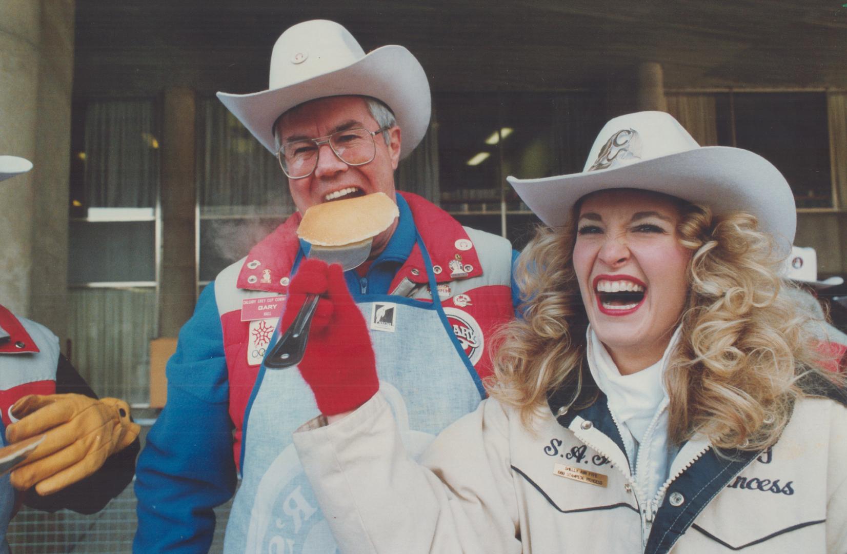 Gary Hall gets a mouthful of pancake from Calgary Stampede Princess Shelly Ann Fyfe at pre-Grey Cup western brunch at Nathan Phillips Square yesterday. More on Grey Cup or Sports, What's On sections