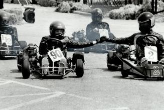Two young competitiors clasp hands as they cross the finish line at the end of a recent go-kart event to raise funds for Youth Assisting Youth organization