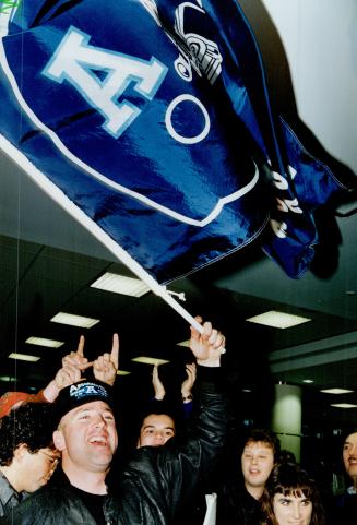 Showing the flag: Argo quarterback Matt Dunigan, who played Sunday despite a fractured collarbone, leads cheering fans at Pearson International Airport yesterday