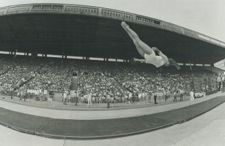 Twisting High in the air in a flying somersault, 16-year-old gymnast Jennifer Diachun, Canadian senior champion, performs for a crowd of about 7,000 a(...)