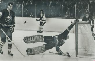 Goalie's calisthenics? Buffalo Sabres' netminder Roger Crozier hangs on to crossbar of cage after spinning around to find puck fired by Maple Leafs' G(...)