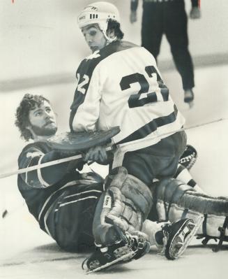 Mask Knocked Off by collision, Vancouver Canucks' goalie Gary Smith looks up at Tiger Williams of Leafs during National Hockey League game at the Gard(...)