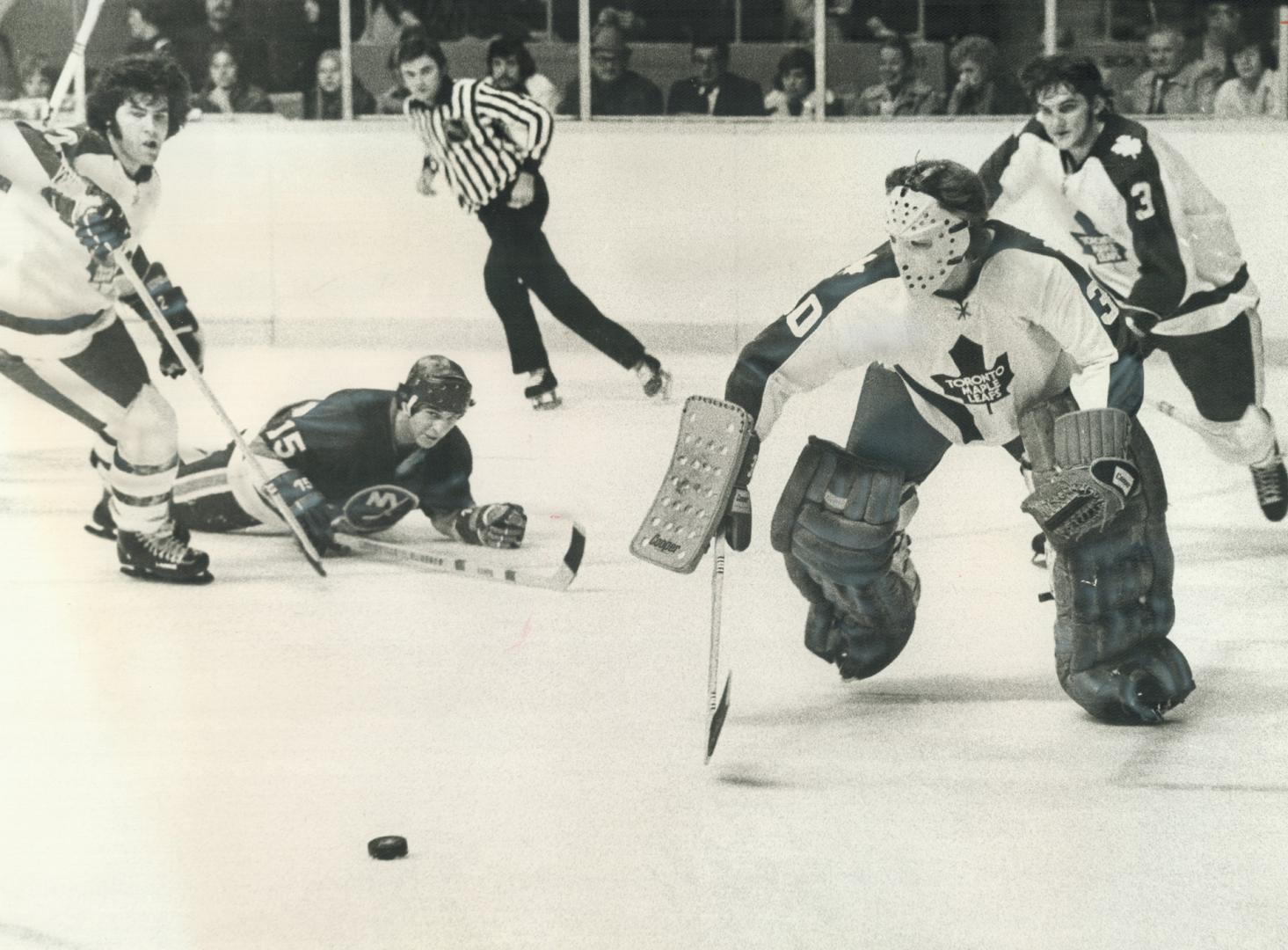 Awkwardly Scrambling out of his crease, Maple Leaf goalie Wayne Thomas pursues loose puck during National Hockey League game at Gardens Saturday night(...)