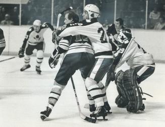 Bear-Hugged Bruin is Wayne Cashman, who is caught up by Brian Glennie in front of Leaf net, Glennie, who recently began wearing a helmet, escaped pena(...)