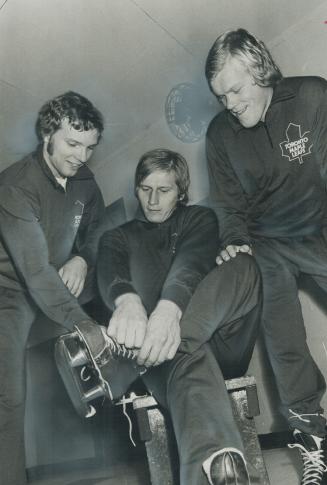 Helping hand: Jorma Valtonen (left) helps Juhani Tamminen don skates while Lauri Mononen watches as trio of Finnish players prepare to join Leaf workout