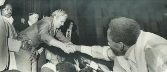 Matching enthusiasm of the crowd, Jamaica's Prime Minister Michael Manley has to be supported as be reaches out to shake hands with one of 1,300 Metro(...)