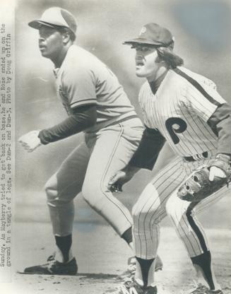 Jays' John Mayberry (left) starts back for bag, guarded by Phils' new first baseman Pete Rose