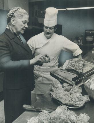 Dinner Guests at the home of Mrs. Pauline McGibbon, new chancellor of the University of Toronto, often are served Steak Manuel. Here Werner Kuenzle, c(...)