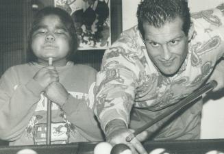 Spreading christmas cheer: Defenceman Bob McGill shoots a little pool with 8-year-old patient Denise Winter as several Maple Leafs paid a visit to the Hospital for Sick Children yesterday