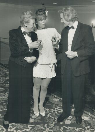 Norma Stewart toasts party organizer or film producer John McGreevy as actress Nikki Pezaro looks on