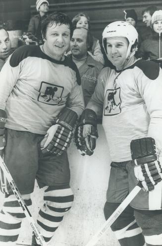 Roy McMurtry , in hockey uniform of the Big Brothers the leadning against the boards chating with Ron Ellis former Leaf Hockey player