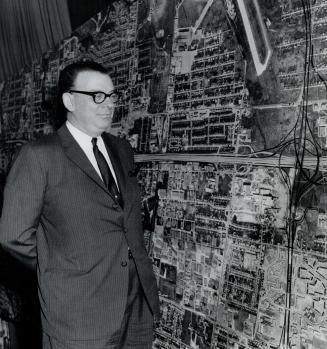 Hon. C.S. MacNaughton at hall showing enlarged photo of the highway portion inquestion