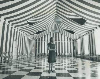 Mrs. Michener standing in newly-decorated tent room. It is now done in striking red and white stripes with checkerboard floor