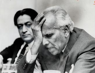 Krishna Menon, controversial former Indian defence minister, cradles his head in his hand during Toronto news conference yesterday. Listening is Romes(...)