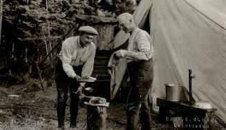 Fry Cobb at left the worlds greatest baseball player and Jack Miner Canadian naturalist at right, photo shows the two in the northern woods on their vocation lost fall frying vensison