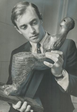 Preparing art exhibit for Ontario pavilion at Expo, Nicholas Fraser admires Seated Woman by Henry Moore of The Archer Fame.Lent by Mr. and Mrs. Clair (...)