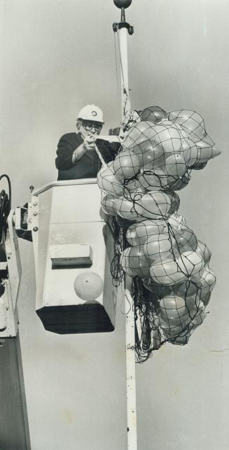 President's up in the air. Donald Mordell, president of Ryerson Polytechnical Institute, rides up in a cherry-picker to release a net of balloons to o(...)