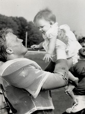 Taking a short rest: Linebacker Don Moen of the Argonauts takes time out from the rigors of training camp in Guelph to greet daughter Chelsea, nine months old