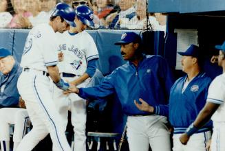 Walk in the park: Paul Molitor is greeted by Jays manager Cito Gaston after scoring on a walk in a five-run first inning against Oakland last night
