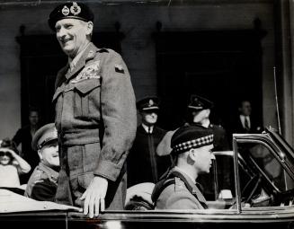 Standing up in his car, Field Marshal Viscount Montgomery gives his famed broad grin to cheering Toronto crowds
