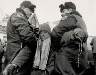 Strong-armed: Dangling a rosary, a protestor is hauled away by police yesterday during pro-lifers' efforts to stop women from entering the Morgentaler abortion clinic