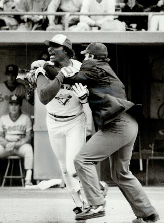 Hold that Blue Jay: Umpire Rocky Roe restrains Lloyd Moseby after the Jay batter was hit by a pitch in the fifth inning