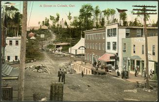 Colorized photograph of people walking on a dirt street of a newly built town with wooden build ...