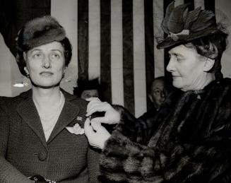 Mrs. Albert Matthews, wife of the lieutenant-governor of Ontario, pins a diamond-studded, gold maple leaf brooch on Her Highness Crown Princess Martha(...)
