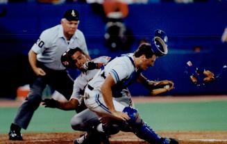 Homecoming surprise, Blue Jays catcher Greg Myers has everything jarred loose but the ball in collision with the Indian's Sandy Alomar