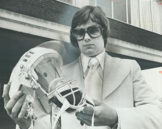 Legal route next, Greg Neeld, who lost an eye in 1973, looks over helmet which he hopes may help him earn berth in NHL