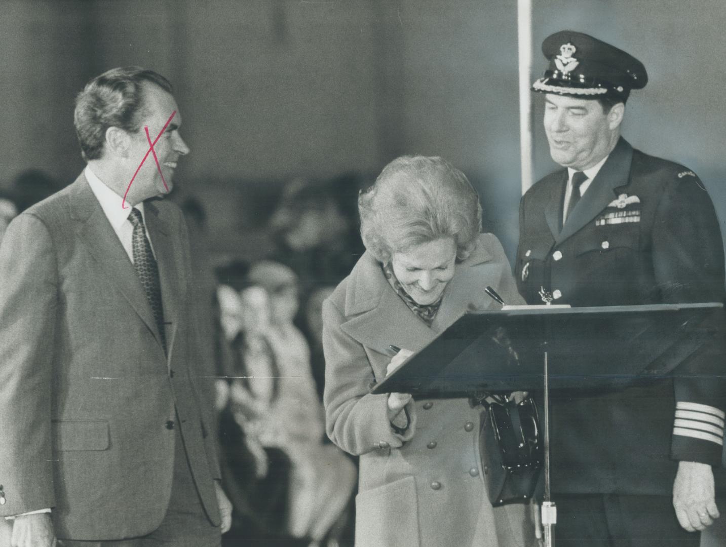 Patricia Nixon, wife of the U.S. president, signs the visitors' book on her arrival at Uplands Airbase, Ottawa, with Col. Ken Wark, base commander, at(...)