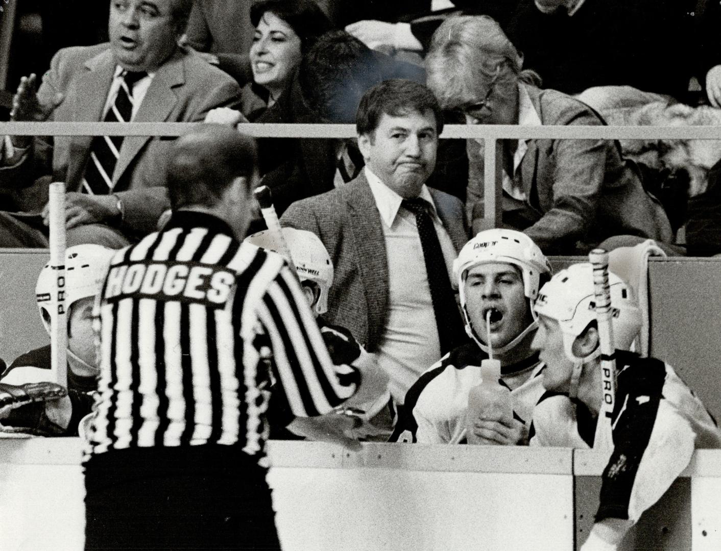 Taste of glum, While linesman Bob Hodges dumps some extraneous litter into the Leaf bench area and defencemen Barry Melrose and Borje Salming quaff fr(...)