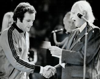 Tom Okker hands with Lieutenant-Governor Ross Macdonald of Ontario and accepts $10,000 first-prize cheque for winning Rothmans International tennis ch(...)