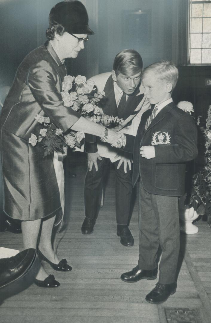 Mrs. Maryon Pearson accepts bouquet of pink roses from Billy Aird, 7, at Upper Canada College where she presented prizes yesterday to the junior schoo(...)