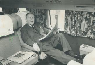 Feet up and relaxed, Liberal Leader Lester Pearson waits aboard a chartered plane at Malton airport for the takeoof