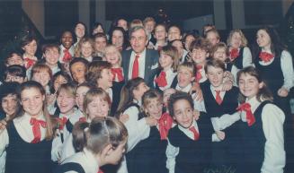 A chorus of christmas cheer. Ontario Premier David Peterson is surrounded by a happy crush of youngsters, members of the Canadian Children's Opera Cho(...)