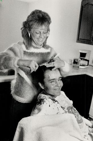 Getting trimmed, Neighbor Lynda Young gives Joe Philion a haircut yesterday in preparation for a community celebration honoring Joe and hundreds of volunteers